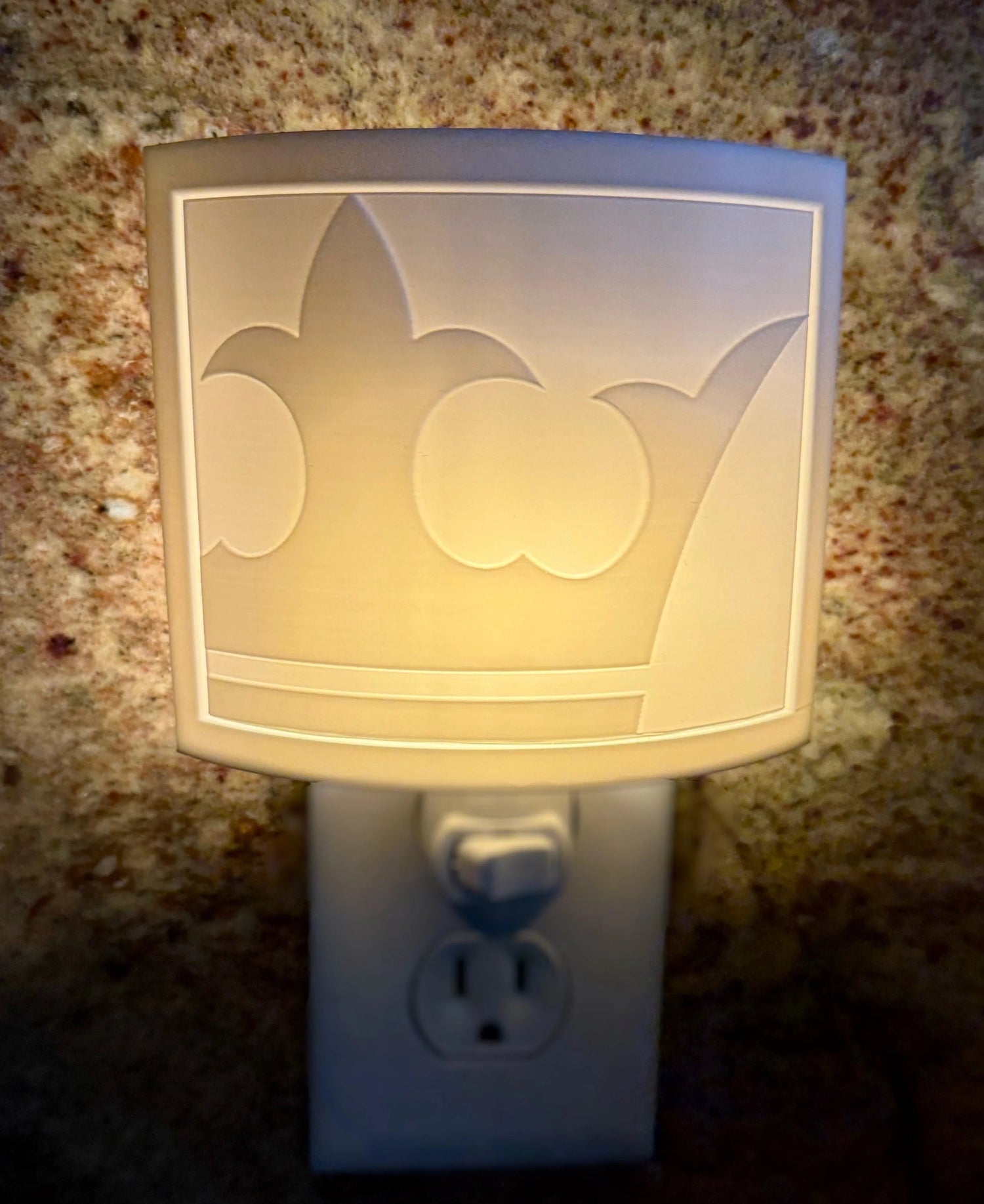 Decorative night light with a crown design on a textured wall.