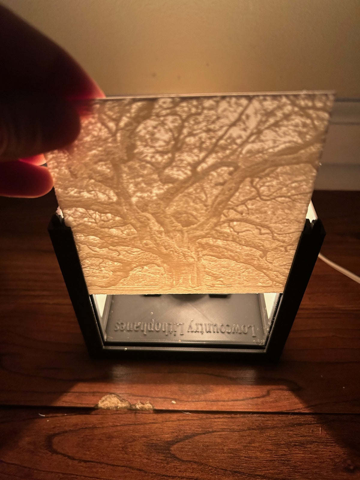 Hand holding a lithophane photo panel above an open lithophane box