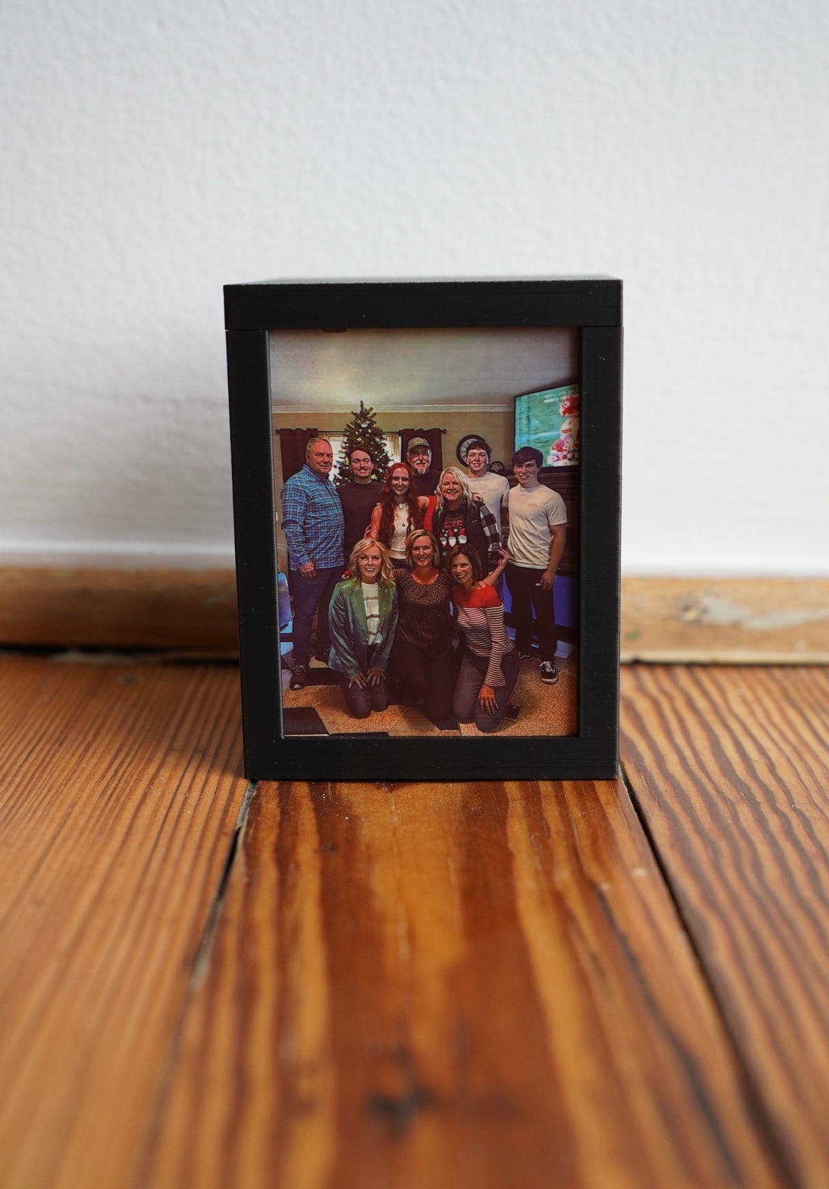 Personalized photo picture frame with a family Christmas photo on a wooden floor