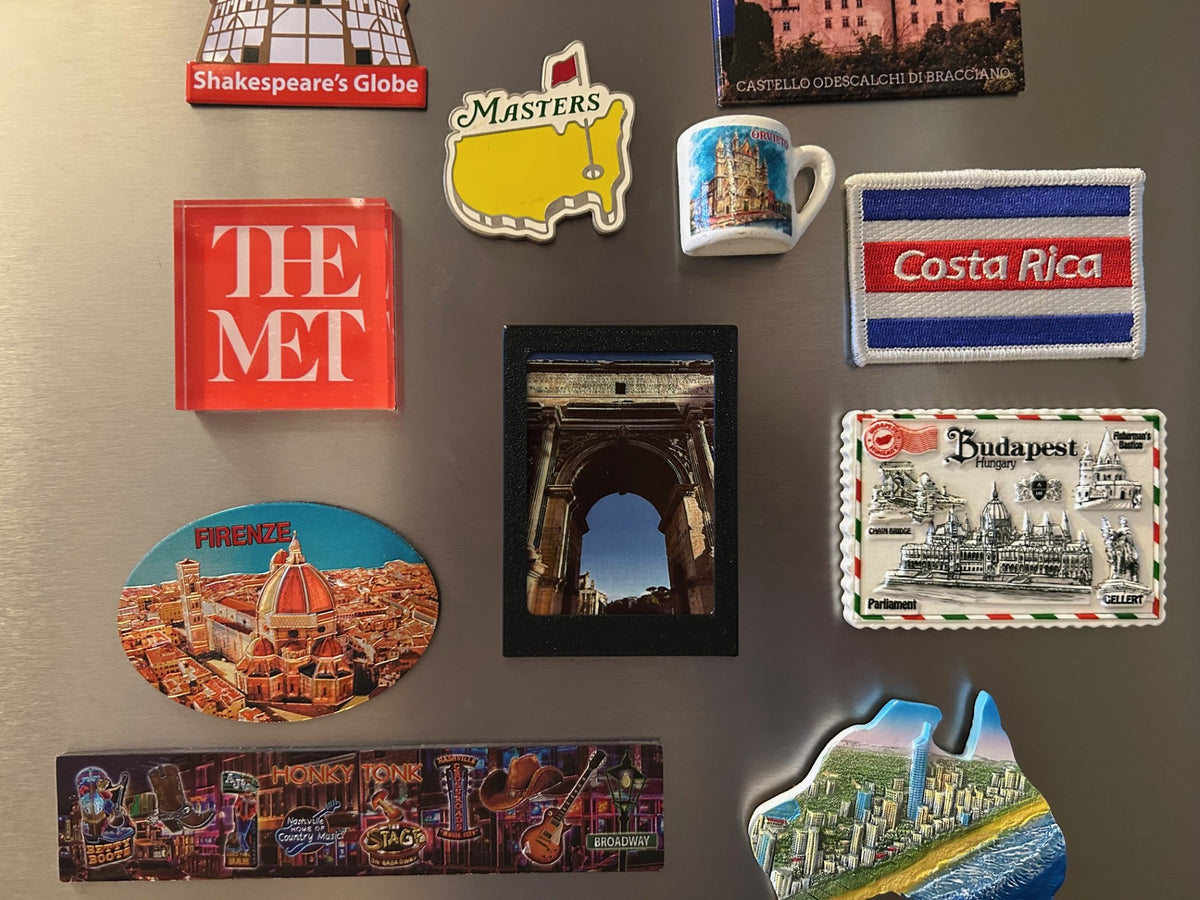 Polaroid fridge magnet holding a custom travel photo on a refrigerator covered with souvenir magnets