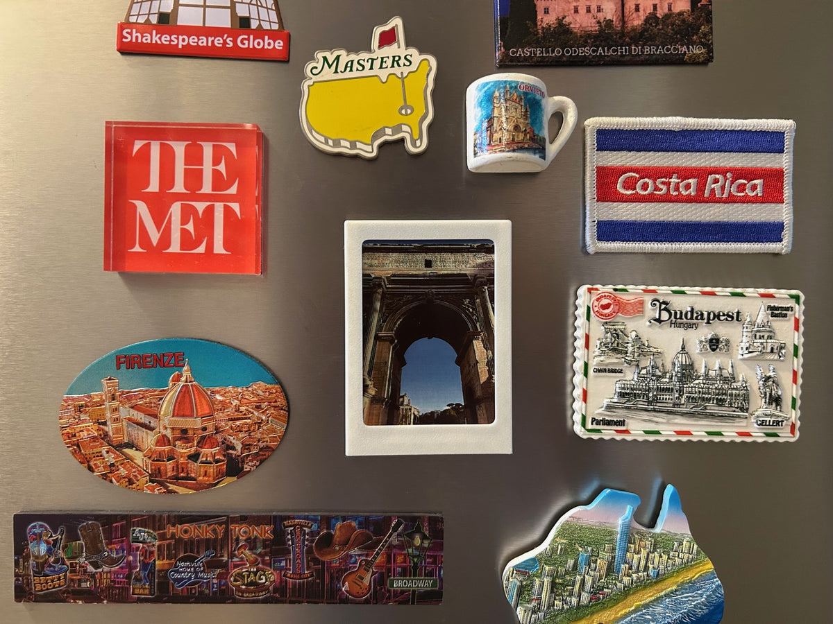Single Polaroid fridge magnet with a custom photo among travel souvenir magnets on a refrigerator